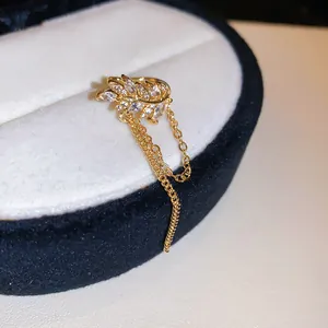 Close-up of gold zircon leaf ear cuff with dangling tassel chains on jewelry box