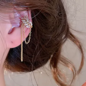 Detail shot of an elegant gold zircon leaf ear cuff with delicate dangling chain tassels