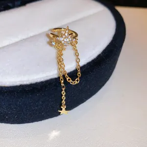 Close-up of elegant gold star ear cuff with zircon detailing and long tassel chain