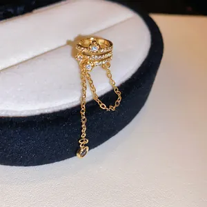 Close-up of gold-plated ear cuff featuring zircon flowers and dangling chain tassels.