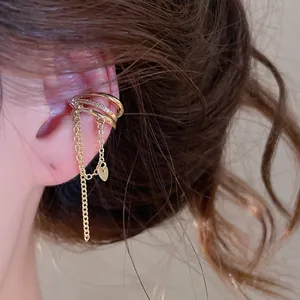 Macro view of a golden zircon ear cuff featuring a delicate dangling heart chain