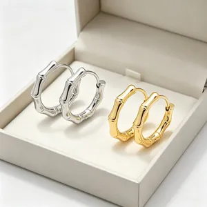 Détail des boucles d'oreilles en acier titane en forme de bambou, finitions or et argent