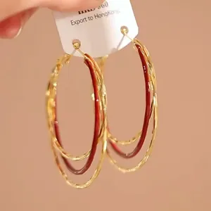 Detailopname van elegante rode en gouden meerlaagse oorringen op een displaykaart