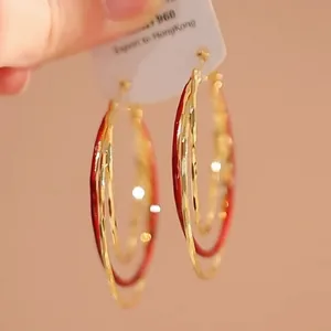 Detailopname van elegante rood-gouden meerlaagse oorringen met een gehamerde textuur