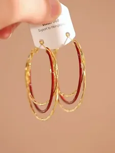 Detail van rode en gouden gelaagde oorringen voorzien van een elegante afwerking