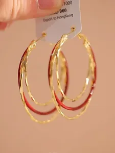 Detailopname van rode en gouden meerlaagse oorringen met elegante rondingen