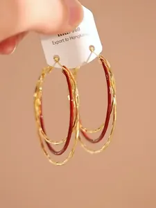 Detail van elegante rode meerlaagse gouden creolen met een gehamerde textuur