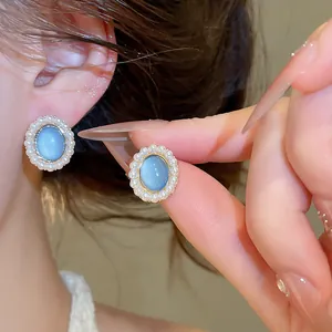 Close-up of elegant oval blue resin pearl earrings showing delicate jewelry details