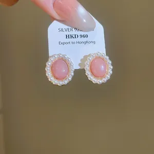 Close-up detail of elegant pink oval resin earrings with white pearl border on S925 tag