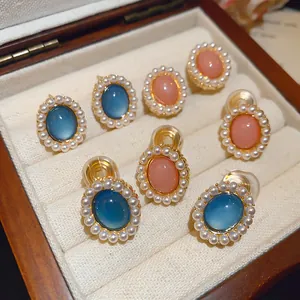 Vintage-style oval resin earrings with pearl borders displayed in a wooden box.