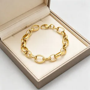 Gros plan d'un bracelet à maillons épais en acier inoxydable doré dans un coffret cadeau