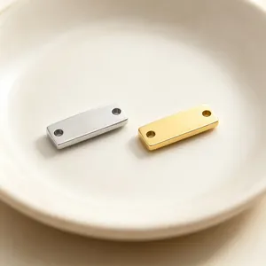 Detailopname van zilveren en gouden roestvrijstalen rechthoekige staafconnectoren met twee gaten