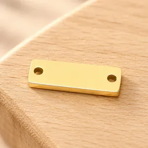 Detailopname van een gepolijste gouden roestvrijstalen rechthoekige connector met twee gaten.