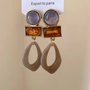 Détail de boucles d'oreilles pendantes géométriques avec résine lavande et ambre