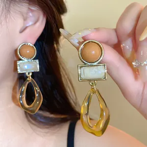 Gros plan de boucles d'oreilles géométriques vintage avec pendentifs en acrylique ambré.