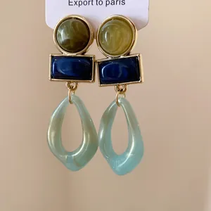 Détail de boucles d'oreilles pendantes géométriques en résine style Maillard vintage