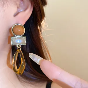Gros plan de boucles d'oreilles pendantes géométriques en acrylique style Maillard sur oreille