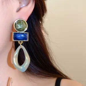 Gros plan sur des boucles d'oreilles géométriques en acrylique vintage vert et bleu