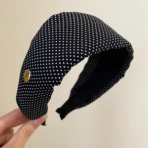 Détail en gros plan d'un large bandeau en tissu à pois noirs et blancs pour femmes