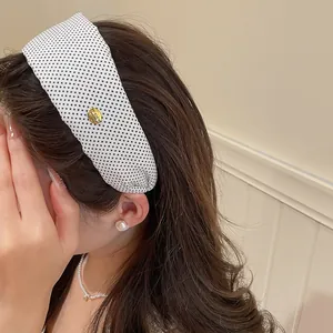 Détail d'un bandeau en tissu à pois noirs et blancs vintage porté par un mannequin