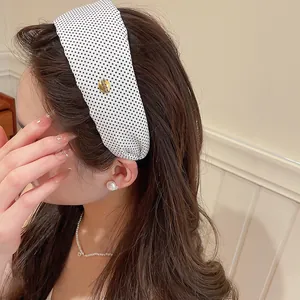 Gros plan du serre-tête large en tissu à pois noirs et blancs sur les cheveux