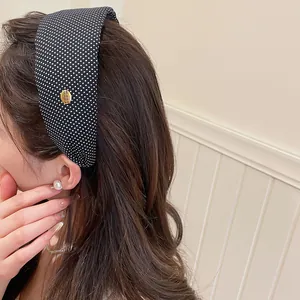 Détail d'un serre-tête large en tissu à pois noirs et blancs au style rétro français