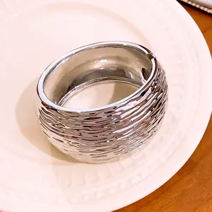 Detailed view of a silver wide bangle featuring unique wrinkled texture and metallic shine
