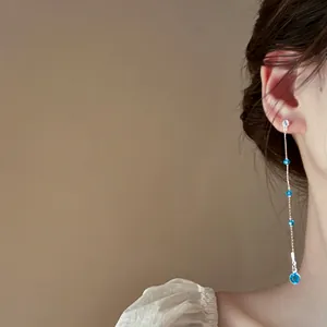 Detailansicht eleganter langer Quastenohrringe mit funkelnden blauen Zirkonia-Steinen