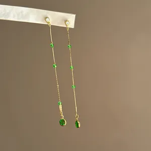Nahaufnahme eleganter langer Quastenohrringe mit grünen Zirkonia-Perlen und Goldketten