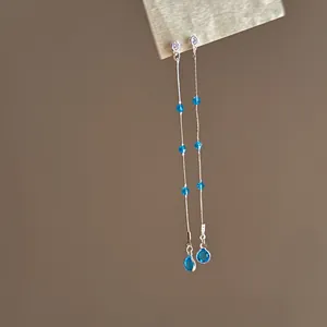 Nahaufnahme langer silberner Quastenohrringe mit eleganten blauen Zirkonia-Perlen