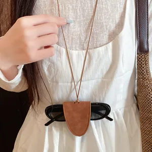 Detailed view of a minimalist brown leather sunglasses holder necklace worn on a white dress