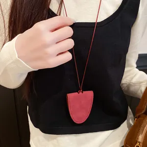 Detail of a red leather eyewear holder necklace pendant on a red cord over a black vest.