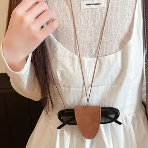 Detailed view of a brown leather glasses holder necklace worn over a white dress