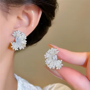 Detailed macro view of 18k white gold plated zircon fan-shaped stud earrings worn on ear