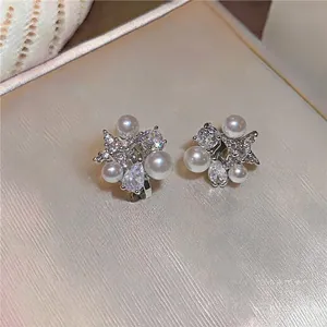 Detailed view of 18k gold plated clip-on earrings with stars, pearls and zircons.