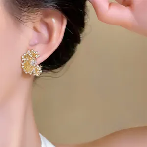 Close-up of 18k gold-plated pleated fan earrings adorned with sparkling cubic zirconia.