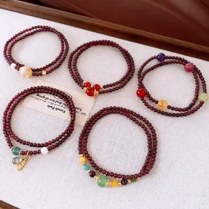 Close-up detail shot of multi-layered garnet bracelets with various colorful gemstone charms.