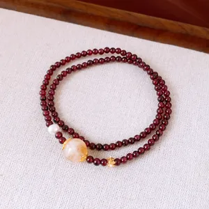 Close-up of a double-layered garnet beaded bracelet with a large stone and pearl