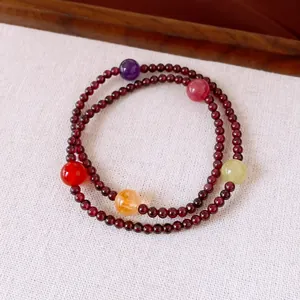 Close-up of a vintage garnet beaded bracelet with multi-colored gemstone accents