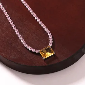 Close-up of silver tennis necklace with pink stones and a large yellow rectangle pendant