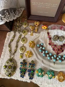 Collectie vintage gouden sieraden met groene en blauwe stenen op kant en bord
