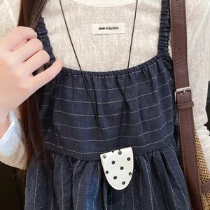 Detailansicht einer weißen Lederbrillenkette mit Polka Dots auf einem gestreiften Kleid