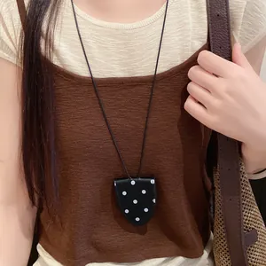 Detailaufnahme einer schwarzen Polka-Dot-Brillenclip-Halskette auf einem braunen Stricktop