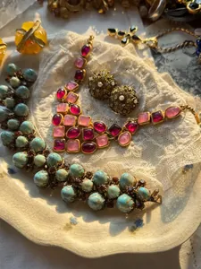 Detail van een 14k vergulde vintage sieradenset met roze stenen en turquoise kralen