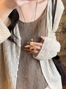 Detailed view of the handmade wooden cat and fish pendant with a woven rope necklace