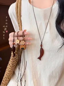 Detailed view of handmade wooden fish and cat pendant necklaces with woven cords