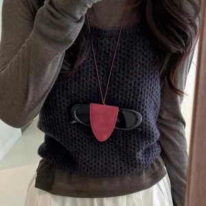 Detail view of a stylish red leather glasses holder necklace on a knit vest.