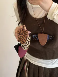 Detail of leopard print leather eyeglass holder necklace accessory worn by model
