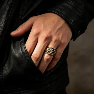 Gros plan d'une bague tête de mort en or vintage portée au doigt sur fond de cuir noir