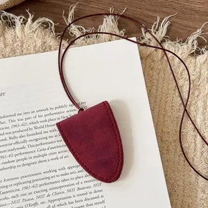 Close-up detail of a minimalist red leather eyewear holder necklace pendant on white card
